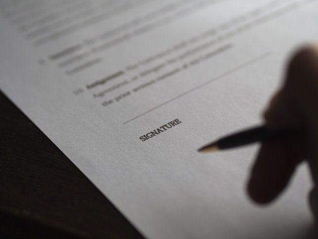 closeup hand and pen at signature line of a contract; highlighting the settlement process in motor vehicle accidents