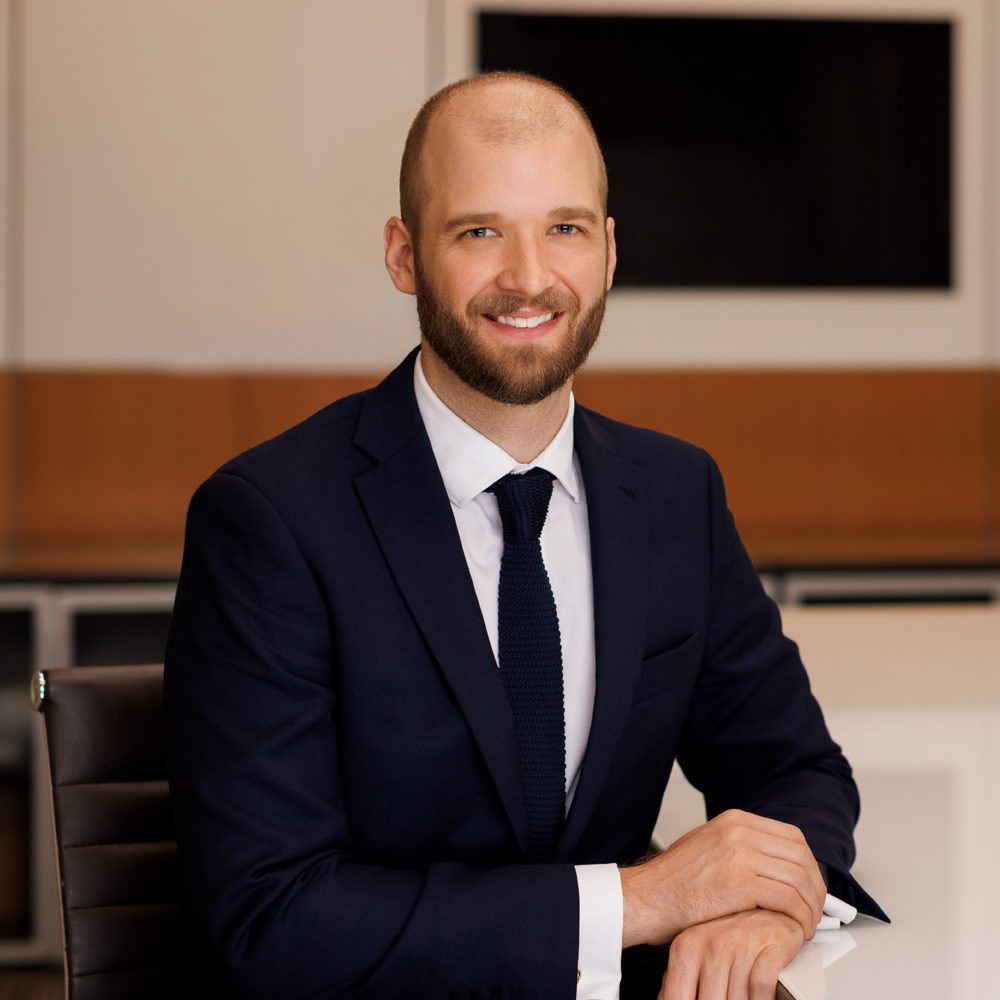 alexander spraggs headshot in Pihl Law Corp firm office in a suit sitting at a white table in a boardroom