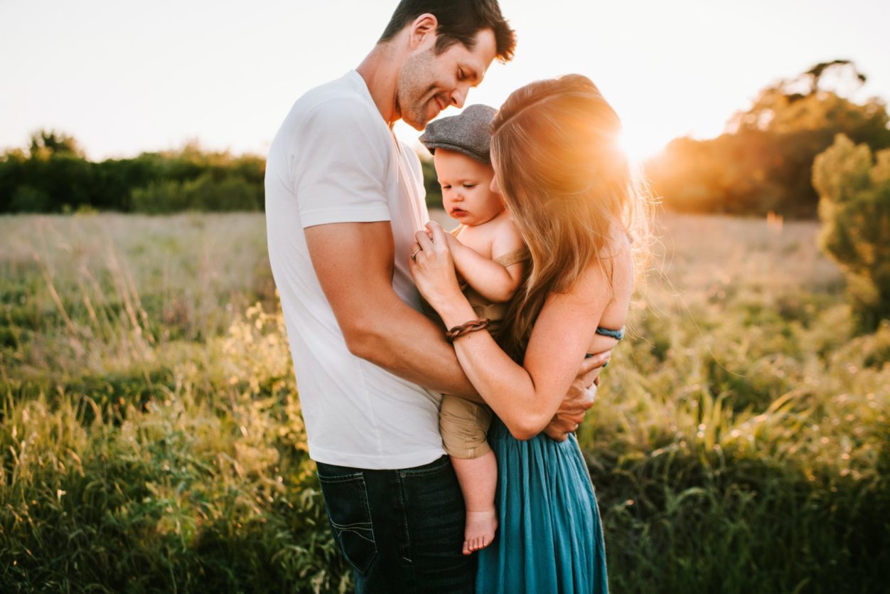 a family picture with baby in a field at golden hour