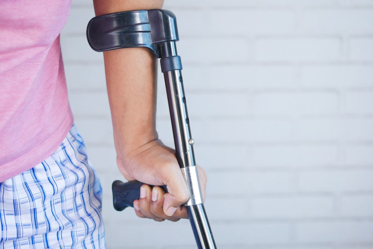 a closeup of a woman's hand holding onto a crutch after an injury