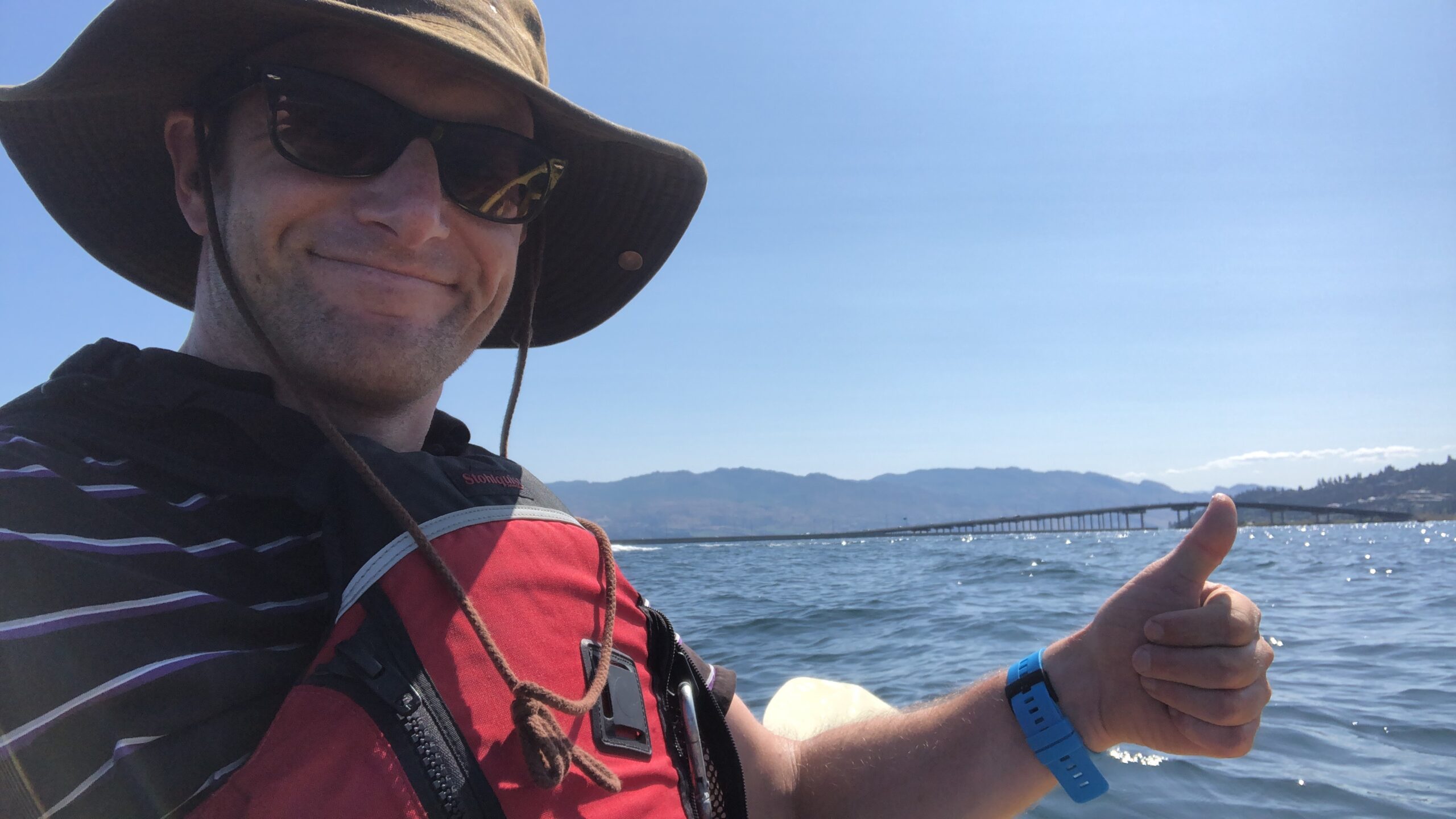Michael Sinclair thumbs up while paddling on Okanagan Lake in summer