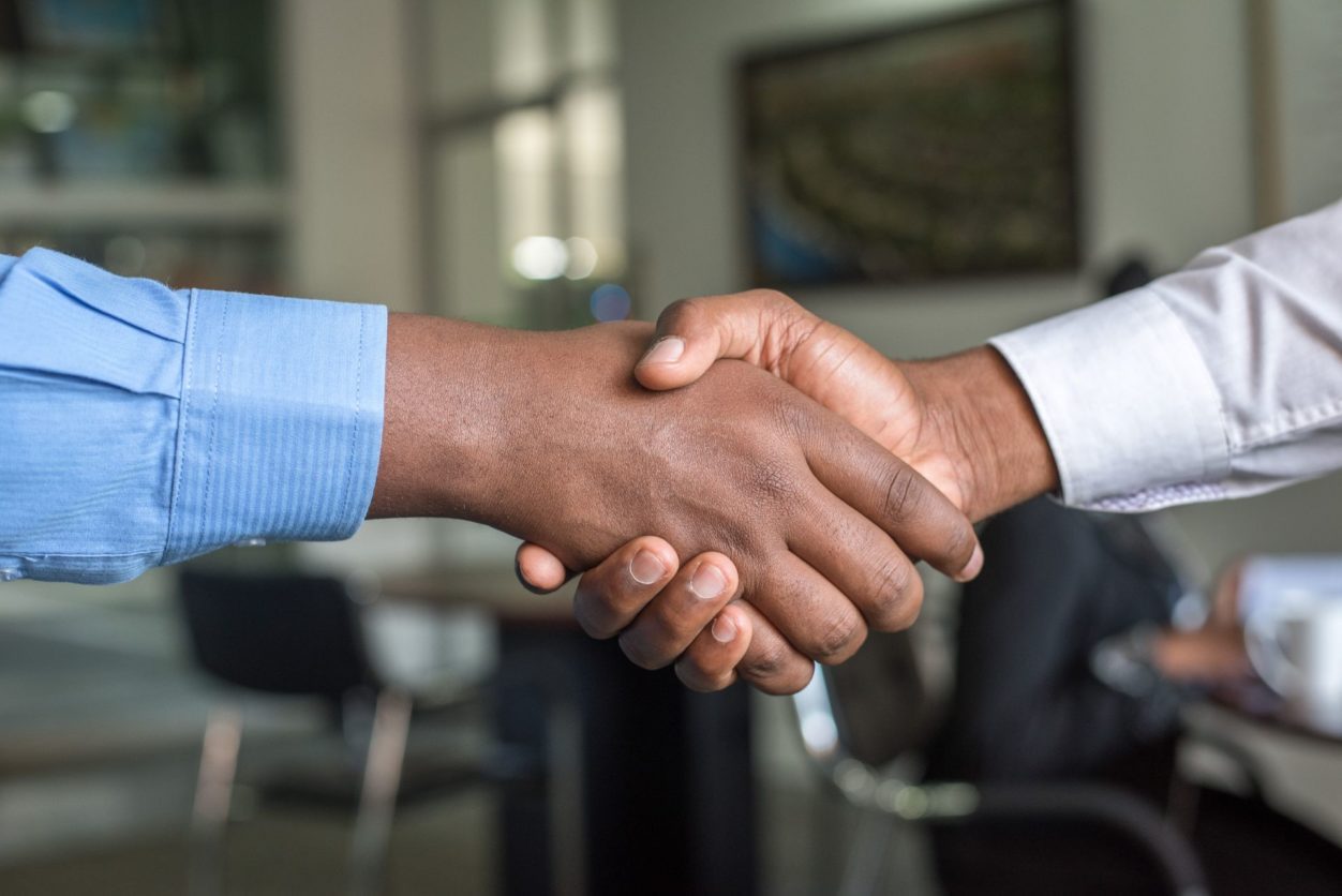 closeup of two hands with business shirt cuffs showing, shaking hands as part of a shareholder agreement